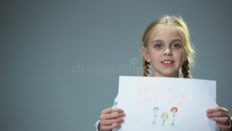 Happy little girl showing family picture into camera, feeling parental love