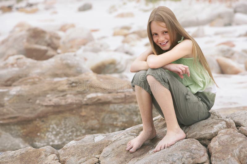 Happy Little Girl Sitting On Rock