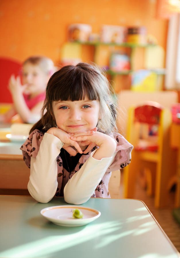 Happy little girl sitting at a table