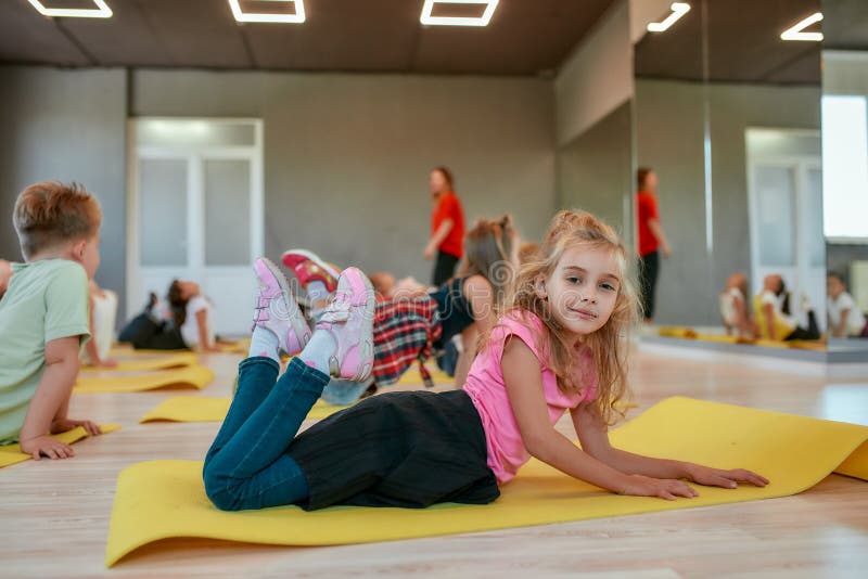 Kids and Sport. Side View of a Happy Little Girl Smiling at Camera while  Lying on Yoga Mat in the Dance Studio. Group of Stock Photo - Image of  gymnastics, friends: 174348358