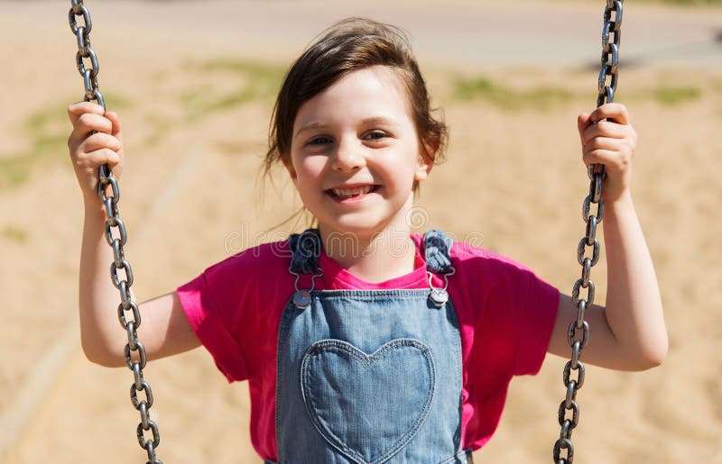 Happy little girl swinging on swing at playground stock photos Happy little girl swinging on swing at playground stock photos