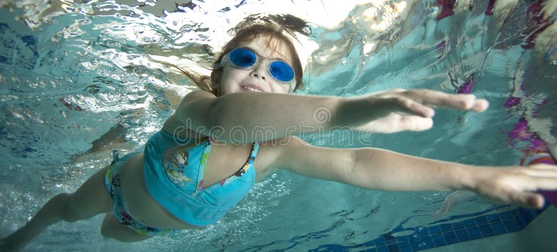 Happy little girl underwater in pool