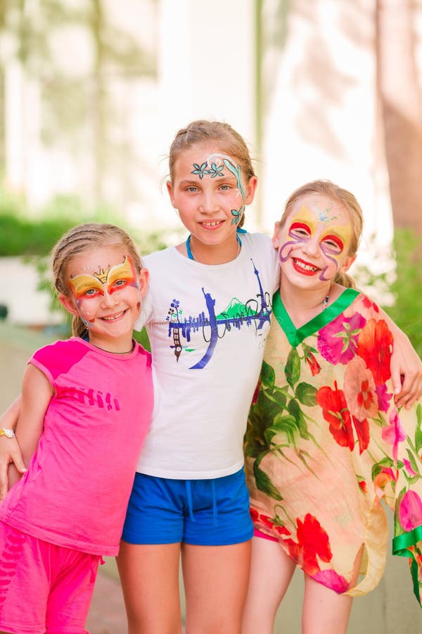 Happy little girls with face art paint in the park.