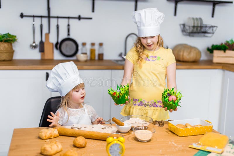 Cute little sisters play and prepare meal at white modern kitchen at home