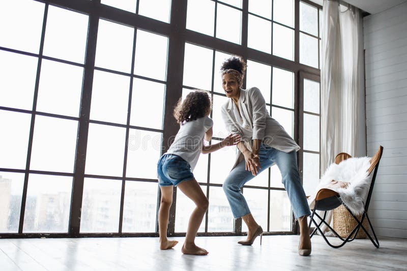 Happy loving afro american family. Young mother and her daughter playing in the nursery. Mom and daughter are dancing on the stock photography Happy loving afro american family. Young mother and her daughter playing in the nursery. Mom and daughter are dancing on the stock photography