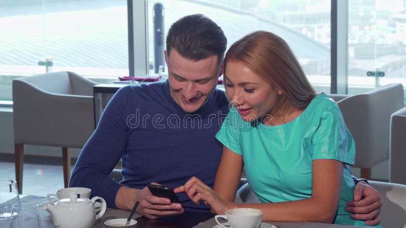 Happy loving couple embracing, using smart phone at the cafe together royalty free stock image Happy loving couple embracing, using smart phone at the cafe together royalty free stock image