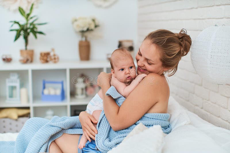 Happy loving mother is sitting on bed with small baby, after breastfeeding royalty free stock image Happy loving mother is sitting on bed with small baby, after breastfeeding royalty free stock image