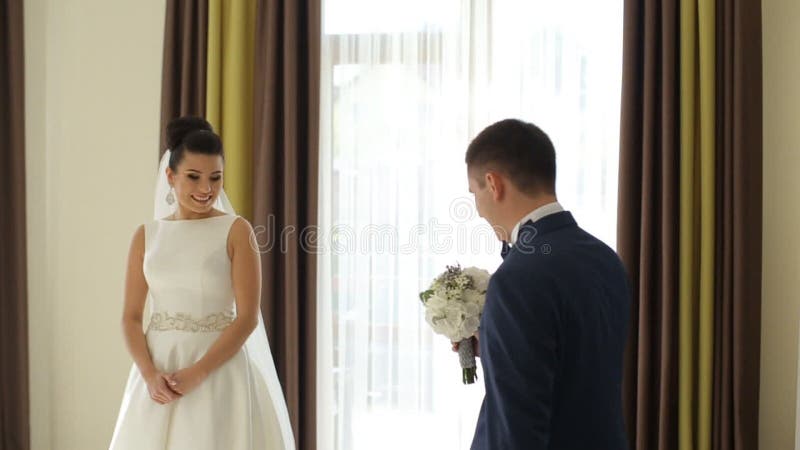 Happy luxury bride and groom standing at window