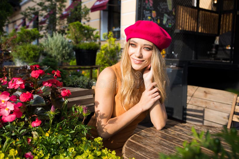 Happy lächelnd ziemlich sorglose Lady in der modischen rosafarbenen Bettdecke, die wegschaut, während sie den schönen, sonnigen S lizenzfreies stockfoto