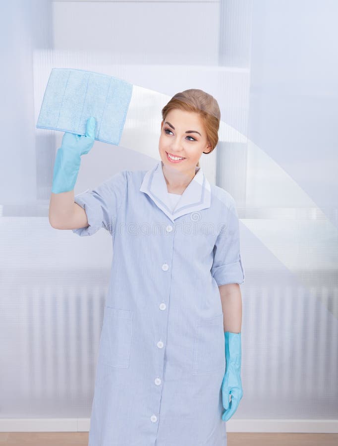 Happy maid cleaning glass stock photo