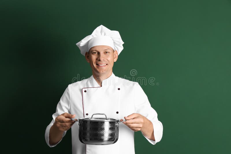 Happy male chef with cooking pot on dark green background royalty free stock photo