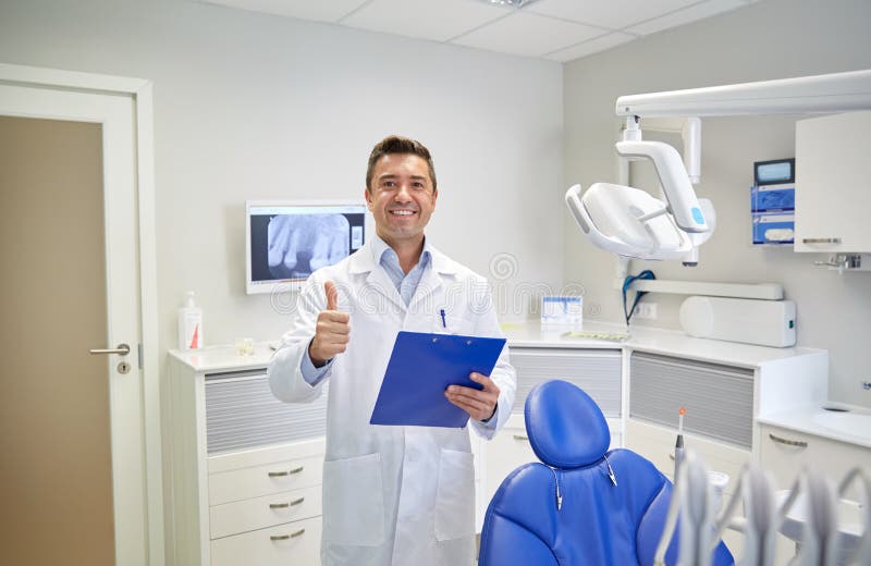 Happy male dentist showing thumbs up at clinic royalty free stock image Happy male dentist showing thumbs up at clinic royalty free stock image