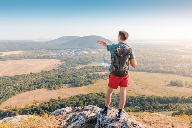 Happy male traveler with a backpack climbed to the top of Mount Shikhan in Bashkiria and admires the views stock photography