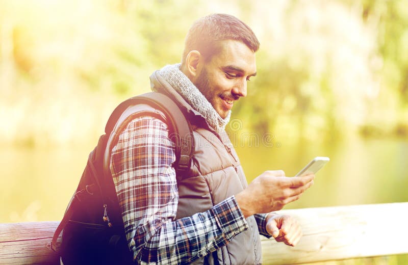 Happy man with backpack and smartphone outdoors