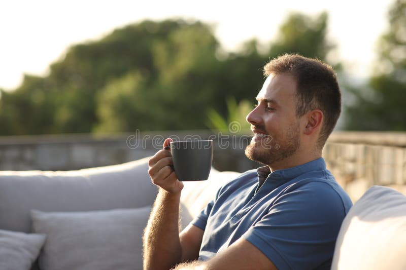 Happy man drinking coffee sitting in an exterior sofa royalty free stock images