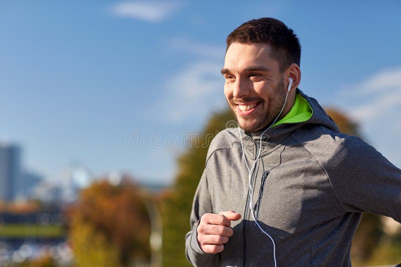 Happy man with earphones running in city