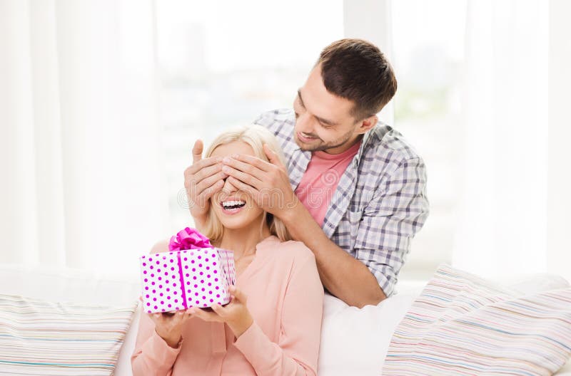 Happy man giving woman gift box at home