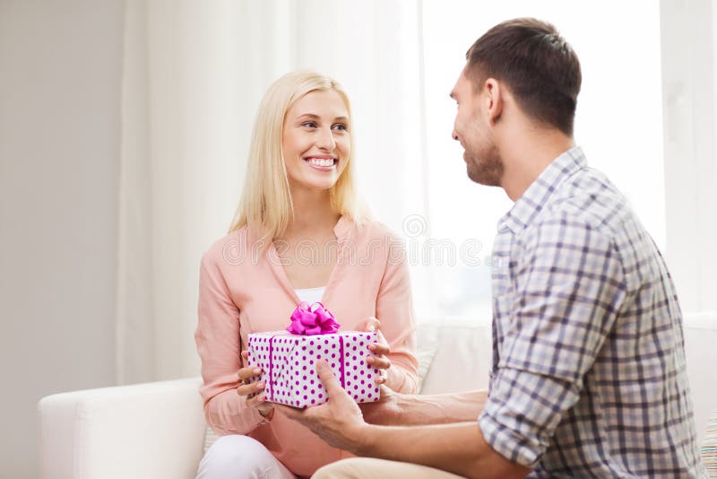 Happy man giving woman gift box at home