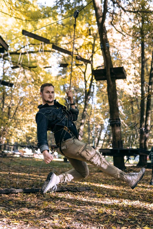 Happy man hanging on a safety rope, climbing gear in an adventure park pass obstacles on the rope road, arboretum, insurance, royalty free stock image Happy man hanging on a safety rope, climbing gear in an adventure park pass obstacles on the rope road, arboretum, insurance, royalty free stock image