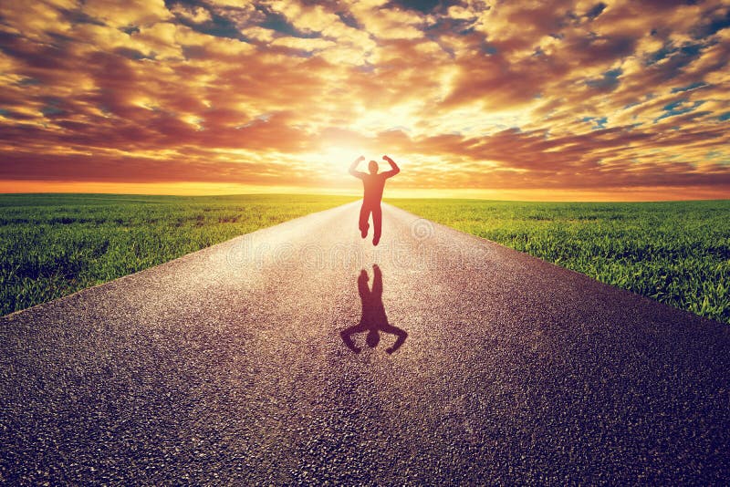 Happy man jumping on long straight road, way towards sunset sun