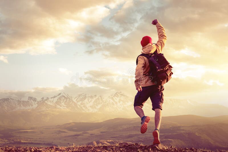 Happy man jumps in winner pose against sunset mountains