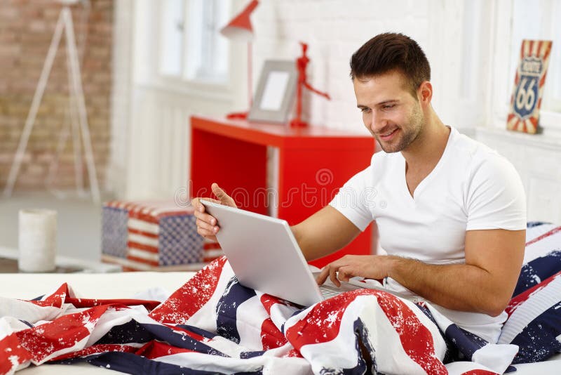 Happy man with laptop in bed royalty free stock photo