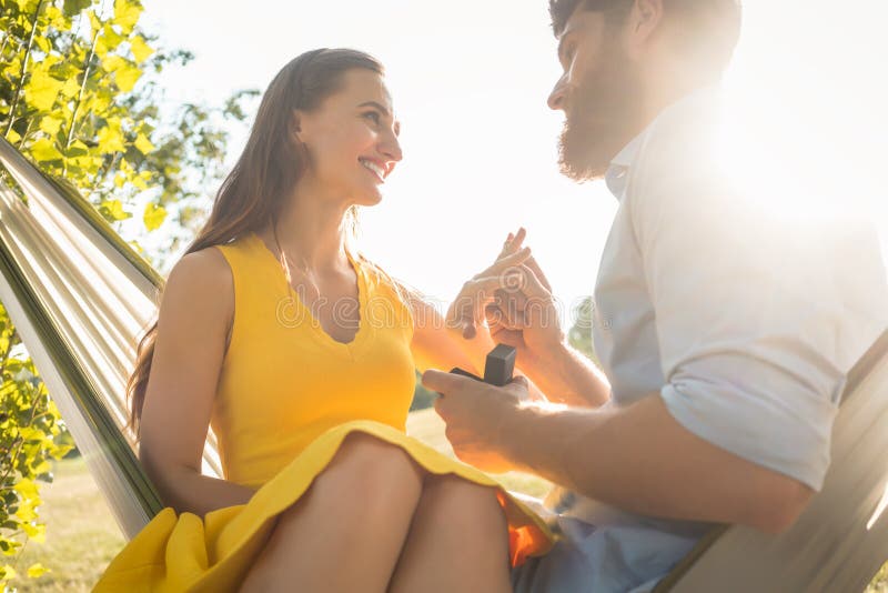 Happy man putting engagement ring on the finger of girlfriend on stock photography Happy man putting engagement ring on the finger of girlfriend on stock photography