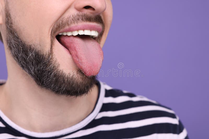 Happy man showing his tongue on purple background, closeup. Space for text royalty free stock image