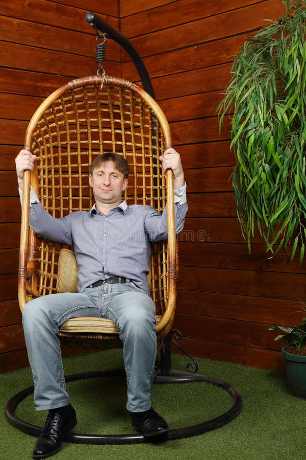 Happy man sits in wicker hanging chair