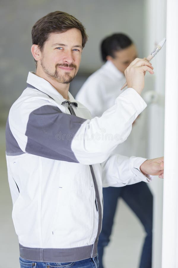 Happy Master Standing with Paint and Brushes in Paint Shop Stock Photo