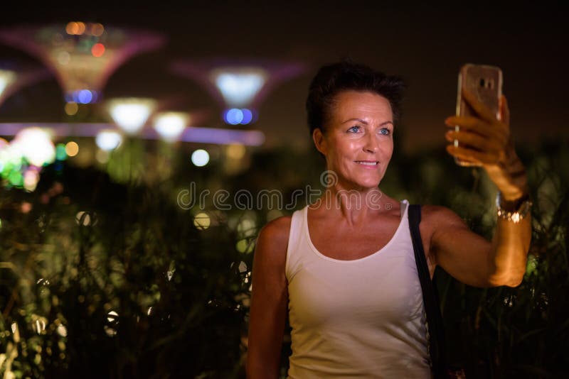 Happy Mature Beautiful Tourist Woman Taking Selfie In The City At Night