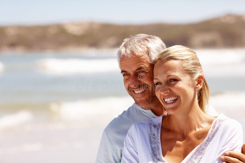 Happy mature couple embracing at the beach stock photo