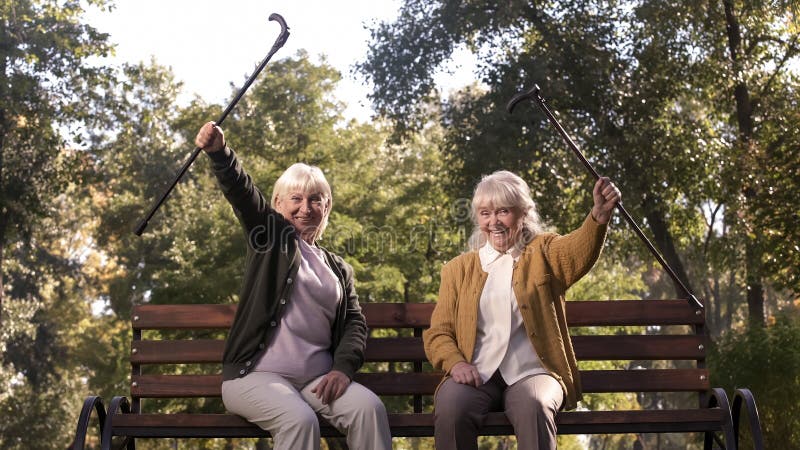 Happy mature female friends rise up hands with sticks and smiling, positive mind