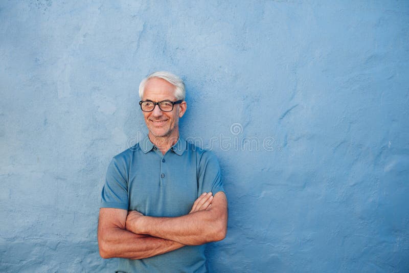 Happy mature man standing with his arms crossed