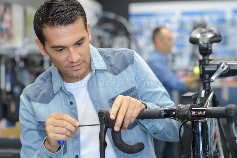 Happy man working on repairing bicycle using screwdriver tool.
