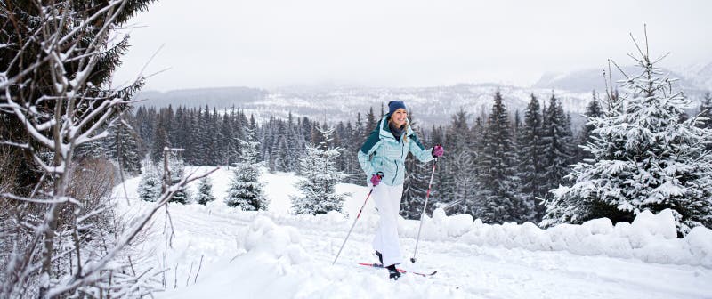 Happy mid adult woman cross country skiing outdoors in winter nature, Tatra mountains Slovakia.