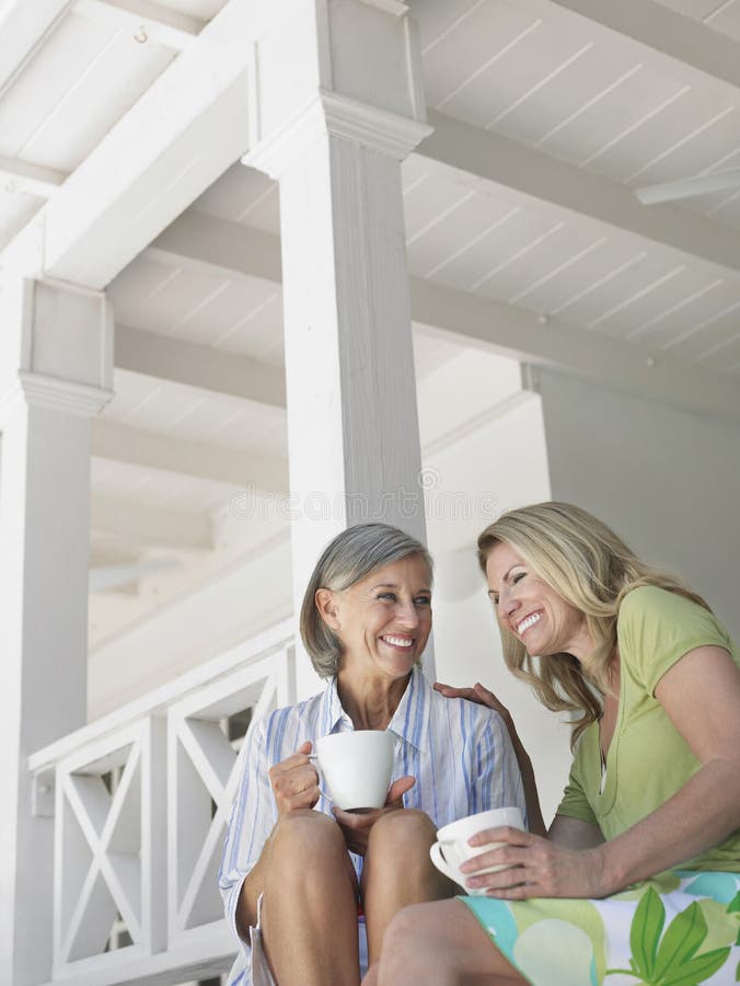 Happy Middle Aged Women On Verandah With Cups