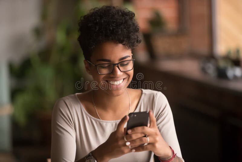 Happy millennial african american woman holding smartphone using ecommerce apps