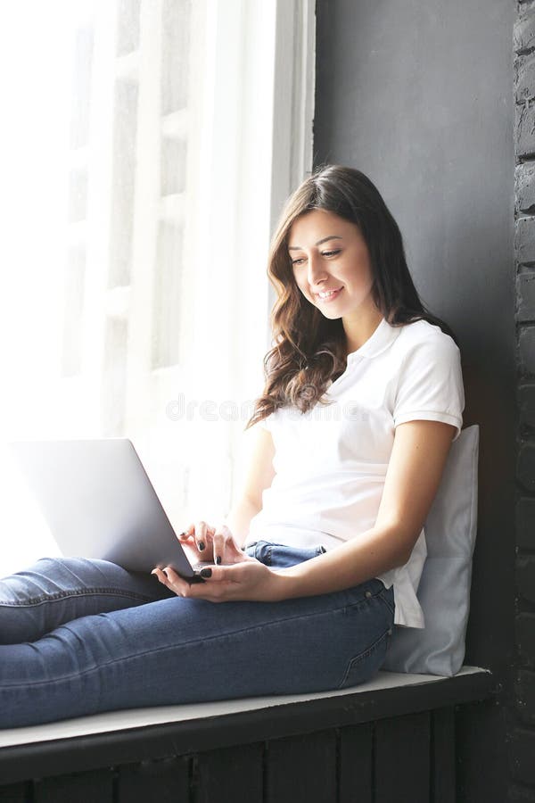 Happy millennial girl w/ laptop on windowsill. Portrait of young woman with diastema gap between teeth. Beautiful smile. Minimal i stock images Happy millennial girl w/ laptop on windowsill. Portrait of young woman with diastema gap between teeth. Beautiful smile. Minimal i stock images