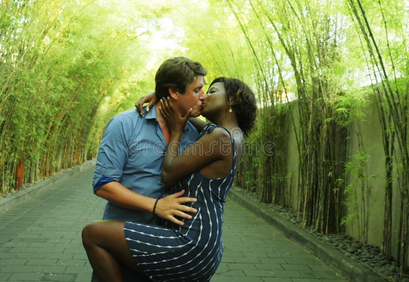 Happy mixed ethnicity couple kissing outdoors with attractive black African American girlfriend or wife and handsome Caucasian man royalty free stock photos Happy mixed ethnicity couple kissing outdoors with attractive black African American girlfriend or wife and handsome Caucasian man royalty free stock photos
