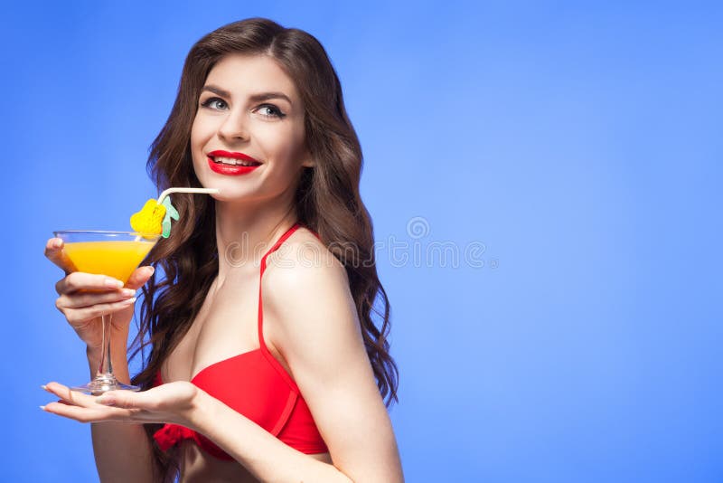 Happy model in red bikini presenting exotic cocktail