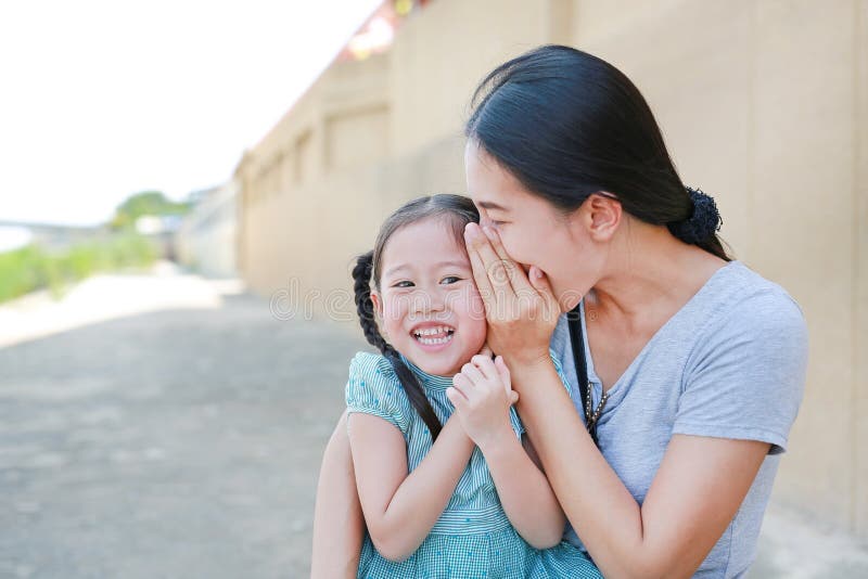 Happy mom whispering a something secret to her little daughter ear. Mother and kid communication concept stock images Happy mom whispering a something secret to her little daughter ear. Mother and kid communication concept stock images
