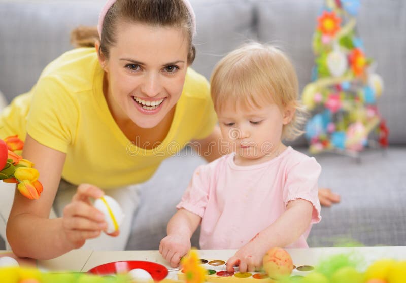 Happy mother and baby making Easter decorations