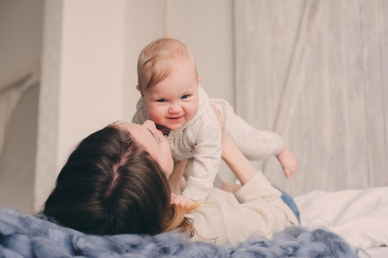 Happy mother and baby playing at home in bedroom. Cozy family lifestyle royalty free stock image Happy mother and baby playing at home in bedroom. Cozy family lifestyle royalty free stock image