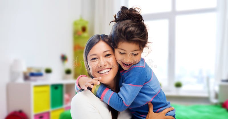 Family, motherhood and people concept - happy mother and daughter hugging over over kids room at home background. Family, motherhood and people concept - happy mother and daughter hugging over over kids room at home background