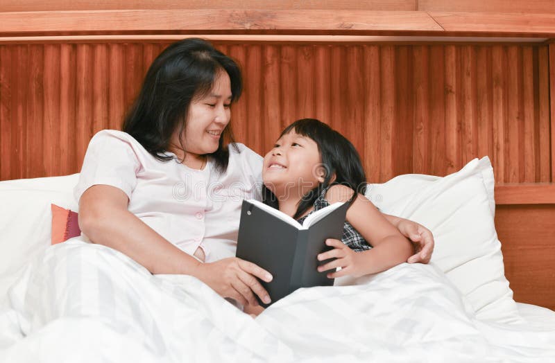 Happy mother and daughter reading book on bed royalty free stock photography Happy mother and daughter reading book on bed royalty free stock photography