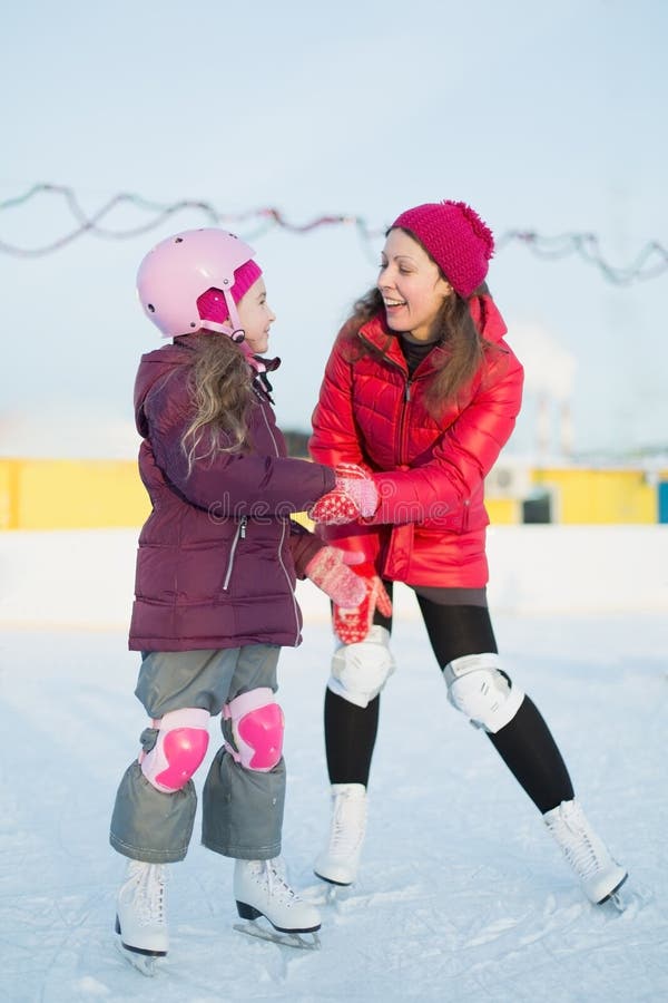 Happy mother and daughter are skating at the outdoor rink stock photos Happy mother and daughter are skating at the outdoor rink stock photos