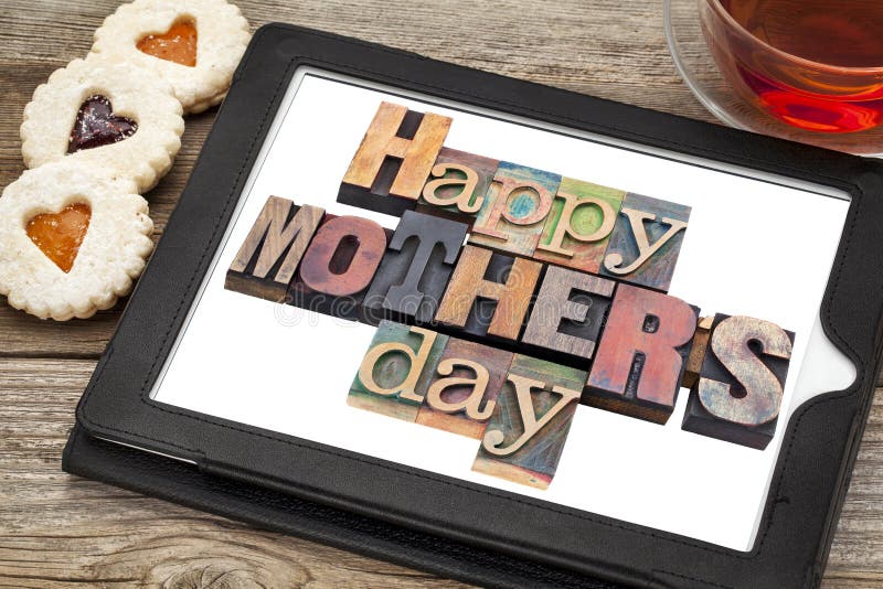 Happy Mother Day in vintage letterpress wood type on a digital tablet with a cup of tea and heart cookies