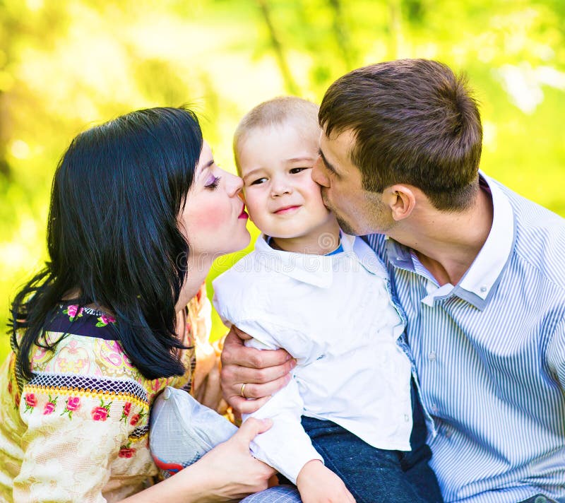 Happy mother and father kissing his little son in park royalty free stock photo Happy mother and father kissing his little son in park royalty free stock photo