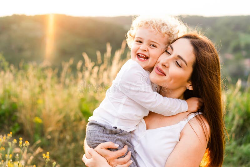 Happy mother hugging her son at sunset.